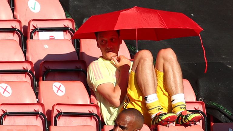 Arsenal&#39;s Mesut Ozil sits with an umbrella in the stands at Southampton