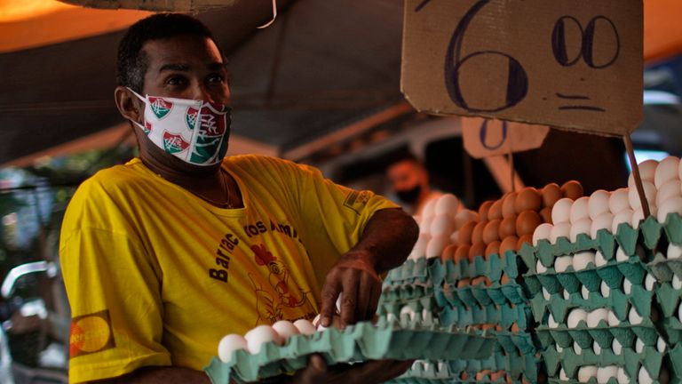 A man wearing a Fluminense face mask prepares eggs for sale after street markets were reopened in Rio de Janeiro