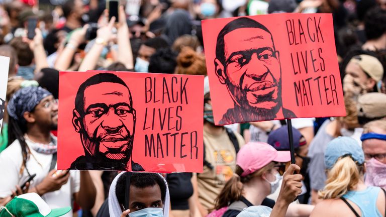 Protesters walk with signs near the White House during George Floyd protests on June 6, 2020 in Washington, DC