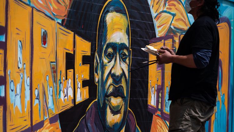 A group of artists paint a mural of George Floyd on the wall outside of Cup Foods, where Floyd was killed in police custody