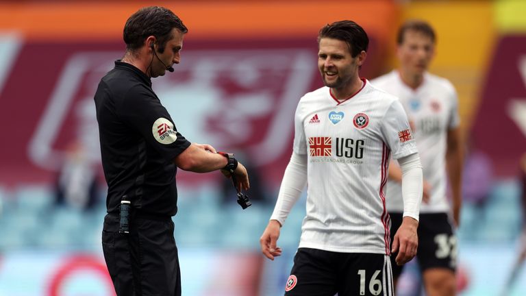 Referee Michael Oliver points to his watch to signal the goal line technology did not give a goal after Sheffield United appeared to score against Aston Villa