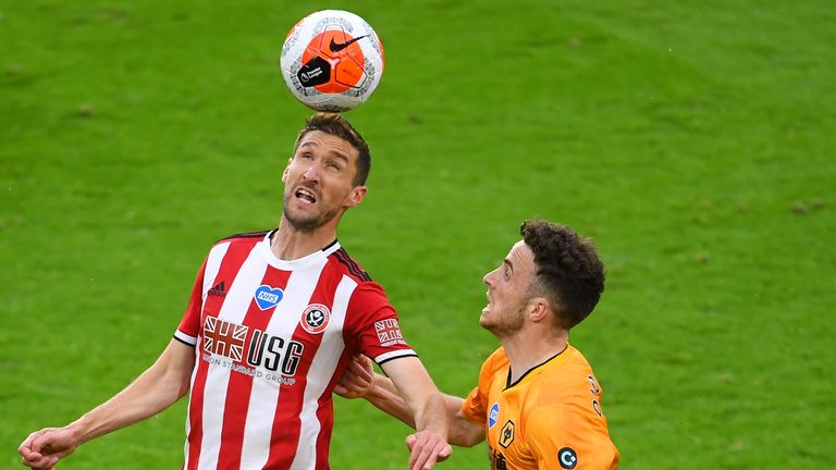 Chris Basham of Sheffield United controls the ball in the air as Diogo Jota of Wolverhampton Wanderers looks on