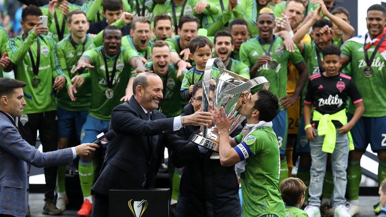 MLS Commissioner Don Garber presents the Philip F. Anschutz Trophy to Seattle Sounders FC team captain Nicolas Lodeiro #10 who then kisses it during a game between Toronto FC and Seattle Sounders FC at CenturyLink Field on November 10, 2019 in Seattle, Washington.