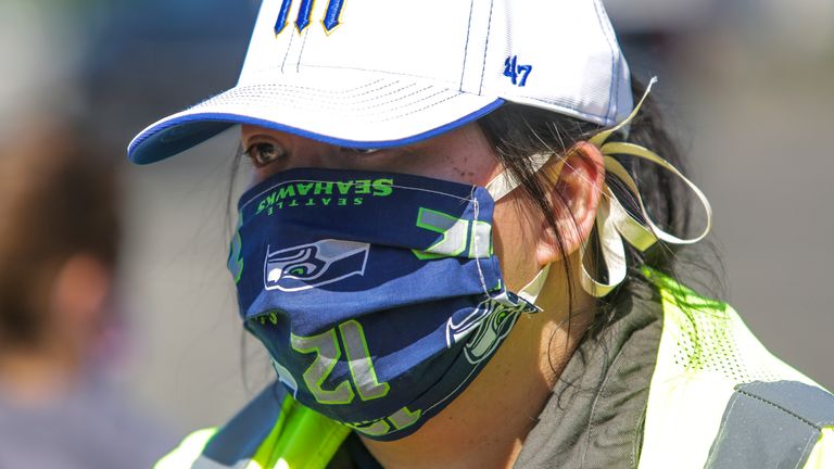 Volunteer Aileen Angeles wears a Seattle Mariners hat and Seattle Seahawks mask as she helps hand out potatoes donated by Washington potato farmers who are giving away a million pounds of excess potatoes, as a result of the food service industry slowdown caused by the outbreak of coronavirus (COVID-19), in Auburn, Washington on May 7, 2020