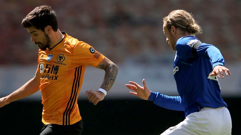 Wolves' Ruben Neves runs with the ball as Tom Davies of Everton looks on