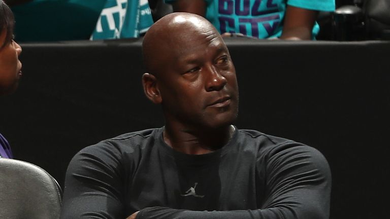 Team owner Michael Jordan sits courtside at a Charlotte Hornets game