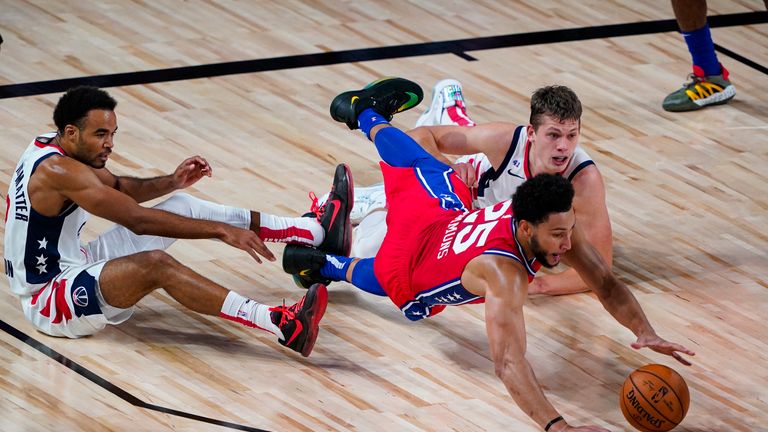 Ben Simmons #25 of the Philadelphia 76ers goes for a loose ball with Jerome Robinson #12 and Moritz Wagner #21 of the Washington Wizards during the first half of an NBA basketball game at The Arena at ESPN Wide World Of Sports Complex on August 5, 2020 in Lake Buena Vista, Florida