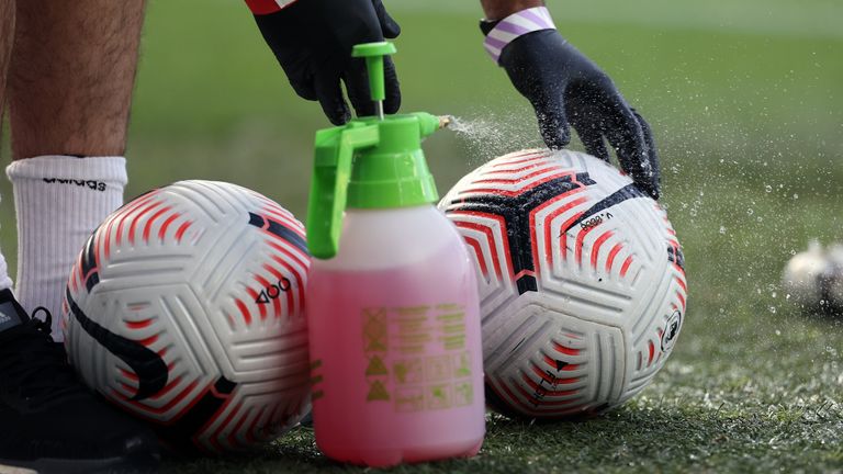 Staff spray match balls with disinfectant prior to kick-off