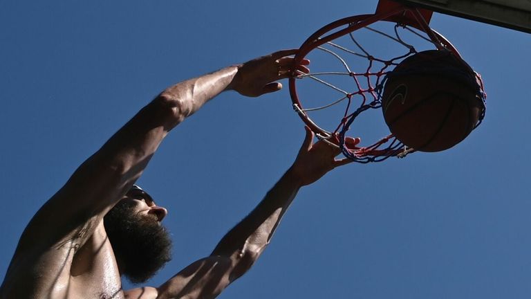 A man dunks the ball as he plays basketball in London Fields park in hot weather east London on June 25, 2020. - Just days after lockdown ended.