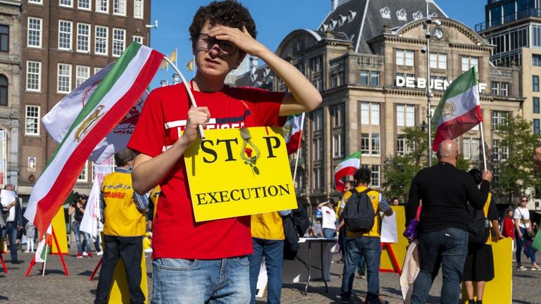 A man holds a sign and a Iranian flag during a demonstration on the Dam Square in Amsterdam