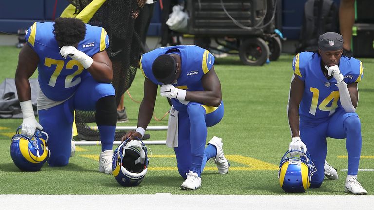 Tremayne Anchrum #72, Bryce Perkins #5 and Nsimba Webster #14 of the Los Angeles Rams kneel during the national anthem prior to a team scrimmage at SoFi Stadium on August 29, 2020 in Inglewood, California