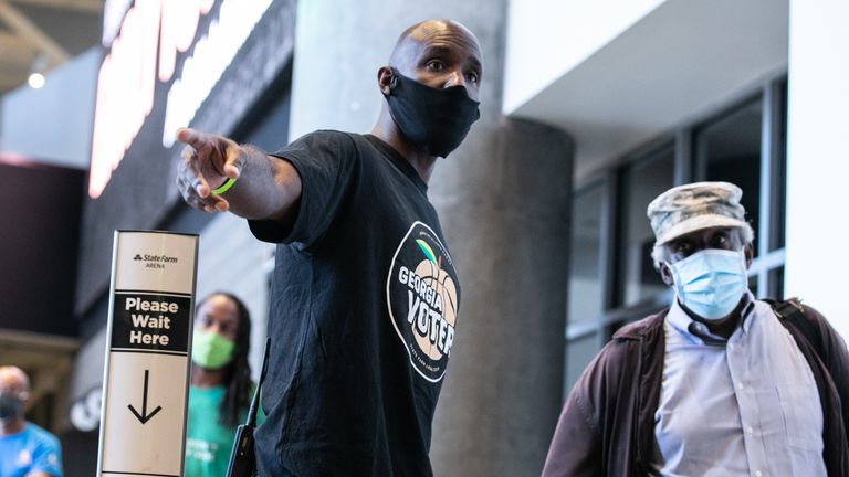 ATLANTA, GA - OCTOBER 12: Atlanta Hawks basketball coach Lloyd Pierce helps voters waiting in line at State Farm Arena to cast their ballot during the first day of early voting in the General Election on October 12, 2020 in Atlanta, Georgia. State Farm Arena is Georgia&#39;s largest early voting location.  Early voting in Georgia runs October 12-30.  (Photo by Jessica McGowan/Getty Images)