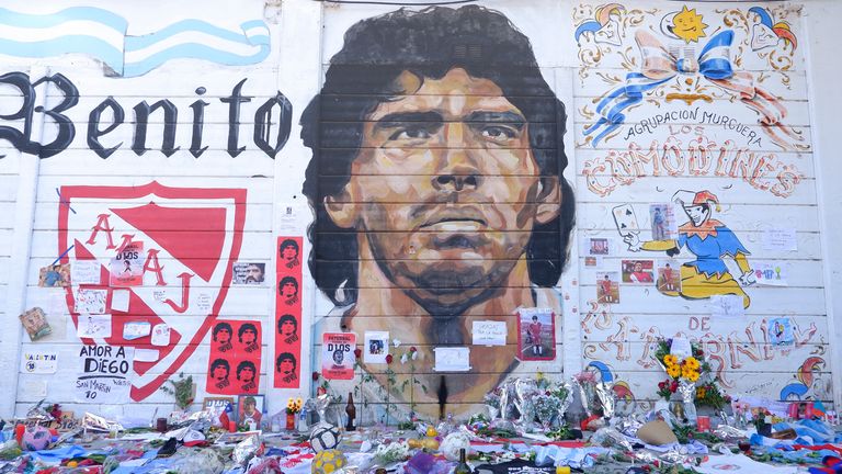 Fans place offerings to late Diego Maradona in front of mural outside Argentinos Juniors' Stadium Diego Maradona