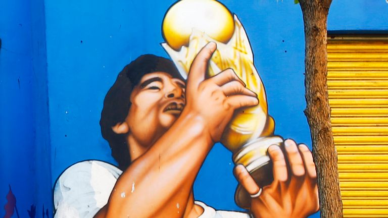 A man walks past murals of Diego Maradona