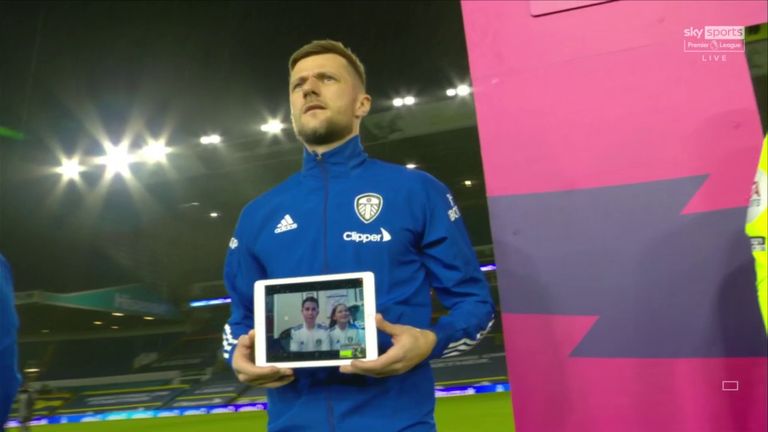 Liam Cooper of Leeds United holds an Ipad displaying a virtual mascot as he leads his team out on to the pitch ahead of the Premier League match between Leeds United and Arsenal at Elland Road on November 22, 2020 in Leeds, England