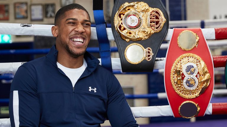 Anthony Joshua poses with his world title belts at the Finchley Boxing Club - credit Matchroom