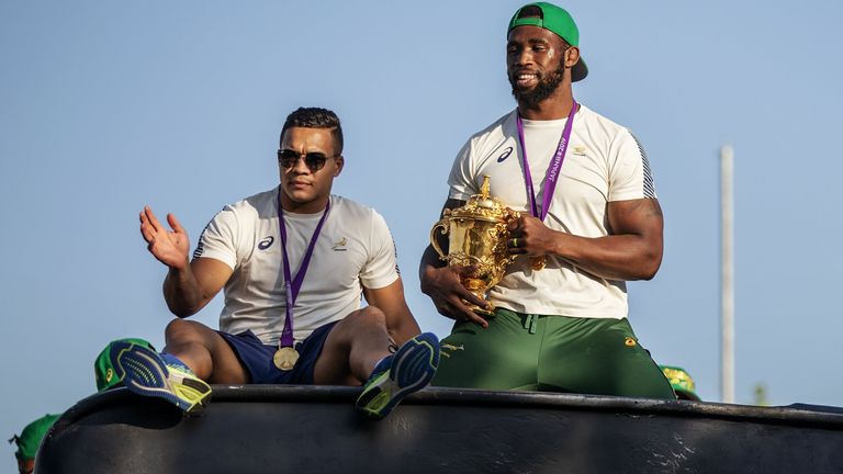 South African wing Cheslin Kolbe and South African Rugby captain Siya Kolisi (R) holds the Web Ellis trophy as the World Cup winner team parades Vilakazi street in Soweto on an open top bus on November 7, 2019 in Soweto, South Africa. (Photo by Michele Spatari / AFP) (Photo by MICHELE SPATARI/AFP via Getty Images)