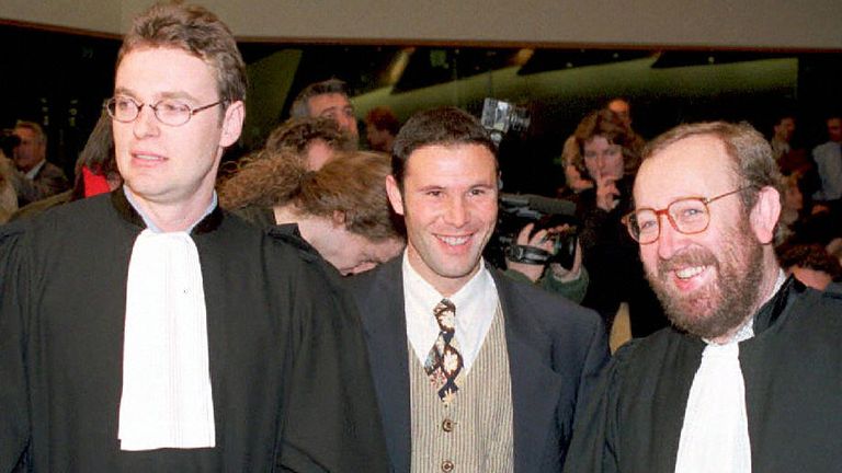 El futbolista belga Jean-Marc Bosman, flanqueado por dos de sus abogados Luc Misson (R) y Jean-Louis Dupont (L), sonríe cuando el Tribunal de Justicia de la Unión Europea dictamina el 15 de diciembre de 1995 que el sistema de transferencia de jugadores entre clubes de fútbol era ilegal . 