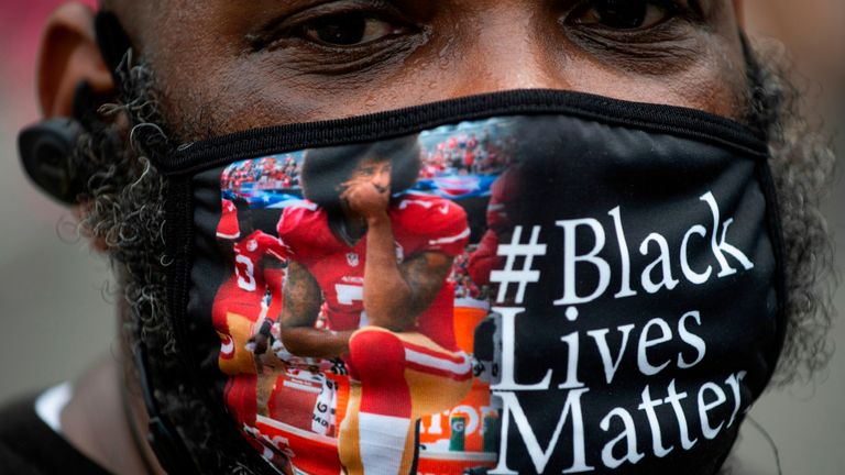 A protester, wearing a face mask featuring Colin Kaepernick kneeling, joins a protest in Washington, DC, against racism and police brutality, on June 6, 2020