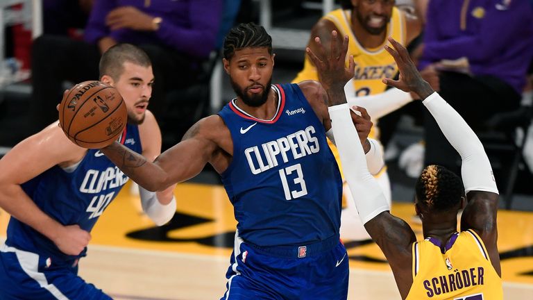 Paul George #13 of the LA Clippers passes around Dennis Schroder #17 of the Los Angeles Lakers during the season opening game at Staples Center on December 22, 2020