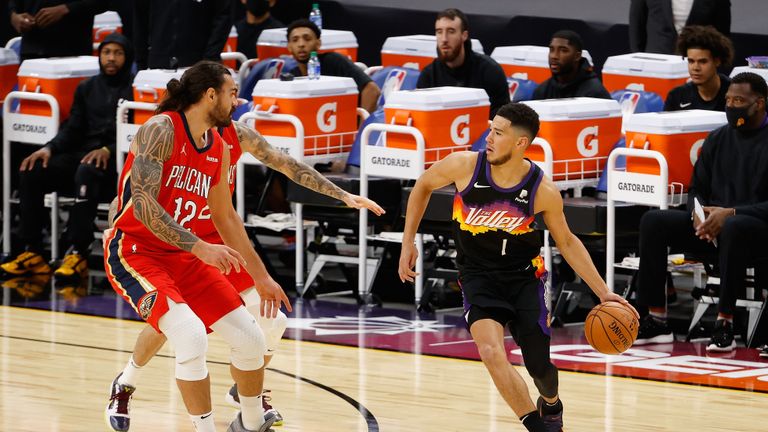 Devin Booker #1 of the Phoenix Suns controls the ball ahead of Steven Adams #12 of the New Orleans Pelicans during the first half of the NBA game at Phoenix Suns Arena on December 29, 2020 in Phoenix, Arizona. 