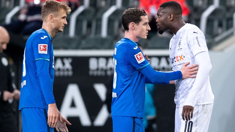 Stefan Posch (L) looks on as Hoffenheim's Sebastian Rudy (C) holds back Borussia Moenchengladbach's Marcus Thuram (R)