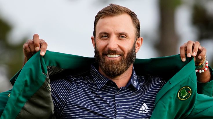 Tiger Woods helps Masters champion Dustin Johnson with his green jacket after his victory at the Masters golf tournament Sunday, Nov. 15, 2020, in Augusta, Ga.  (AP Photo/Matt Slocum)