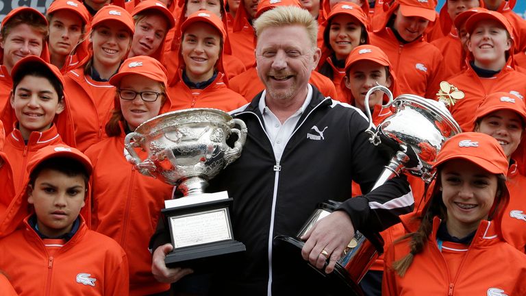 Former Australian Open champion Boris Becker holds the trophies of the men's singles and women's singles with ball kids, ahead of the first matches of this year's Australian Open tennis championship in Melbourne, Australia, Monday, Jan. 19, 2015. (AP Photo/Lee Jin-man)