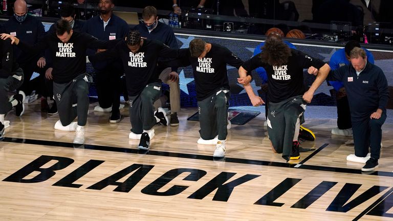 Milwaukee Bucks join arms as they kneel during the national anthem before an NBA basketball first round playoff game against the Orlando Magic