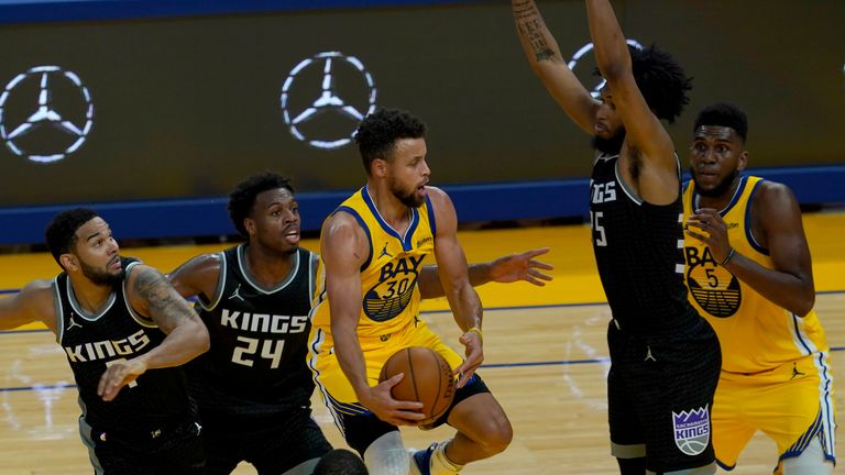Golden State Warriors guard Stephen Curry, middle, prepares to pass the ball to forward Kevon Looney (5) against the Sacramento Kings
