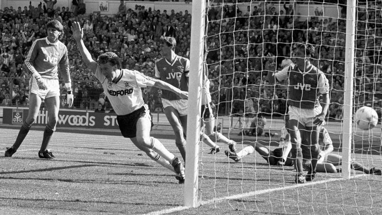 Luton Town's Danny Wilson (fourth l) celebrates scoring the equalizing goal to make the score 2-2, watched by teammates Mark Stein (l), Kingsley Black (sixth l, behind post) and Brian Stein (r, hidden), and Arsenal's Gus Caesar (second l), John Lukic (third l), Tony Adams (fifth l), Kenny Sansom (r) and Nigel Winterburn (r, hidden)