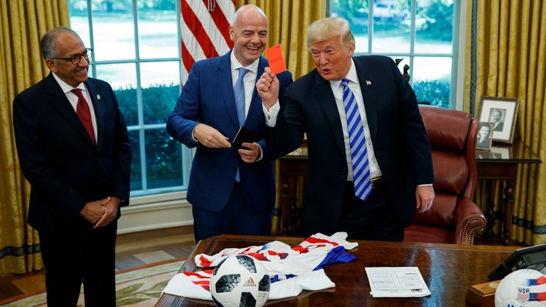 President Donald Trump holds up a red card during a meeting with FIFA president Gianni Infantino, center, and United States Soccer Federation president Carlos Cordeiro, left, in the Oval Office of the White House, Tuesday, Aug. 28, 2018, in Washington