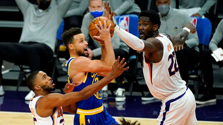 AP - Golden State Warriors guard Stephen Curry, center, drives between Phoenix Suns center Deandre Ayton, right, and forward Mikal Bridges