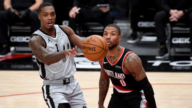 San Antonio Spurs guard Lonnie Walker IV, left, passes the ball on Portland Trail Blazers guard Damian Lillard, right, during the second half of an NBA basketball game in Portland, Ore., Monday, Jan. 18, 2021. (AP Photo/Steve Dykes)


