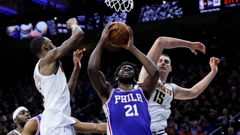 Philadelphia 76ers&#39; Joel Embiid goes up for a shot between Denver Nuggets&#39; Will Barton and Nikola Jokic during the second half of an NBA basketball game
