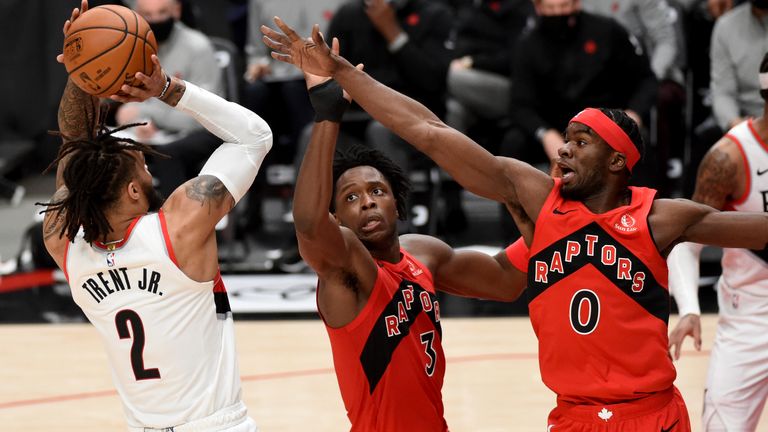 Portland Trail Blazers guard Gary Trent Jr., left, shoots the ball over Toronto Raptors forward OG Anunoby, center, and guard Terence Davis, right, during the second half of an NBA basketball game in Portland