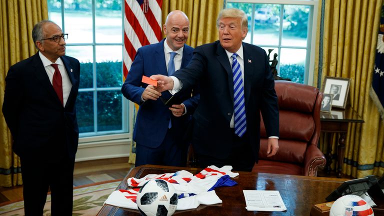 President Donald Trump jokes around with a red card during a meeting with FIFA president Gianni Infantino, center, and United States Soccer Federation president Carlos Cordeiro in the Oval Office of the White House, Tuesday, Aug. 28, 2018, in Washington