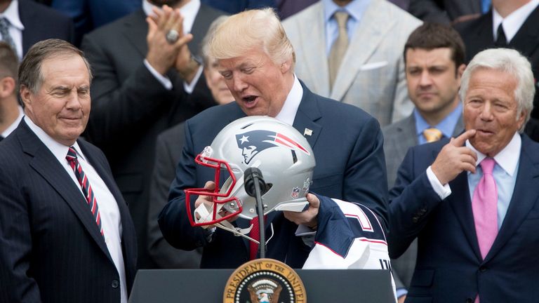 In this April 19, 2017, file photo, President Donald Trump. flanked by New England Patriots head coach Bill Belichick, left, and owner Robert Kraft, holds a New England Patriots football helmet and jersey during a ceremony on the South Lawn of the White House in Washington, where he honored the Super Bowl Champion New England Patriots for their Super Bowl LI victory