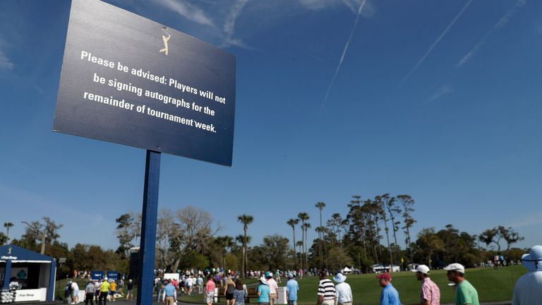 Fans walk pass a sign advising fans that players will not be signing autographs, during the first round of The Players Championship golf tournament Thursday, March 12, 2020 