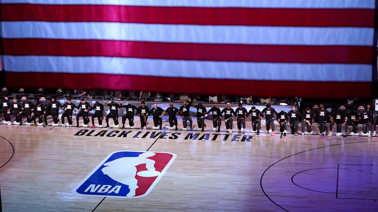 Members of the Orlando Magic and Brooklyn Nets kneel around a Black Lives Matter logo during the national anthem before the start of an NBA basketball game on July 31, 2020, in Lake Buena Vista, Fla. (AP Photo/Ashley Landis)           
