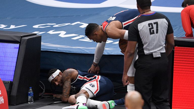 Washington Wizards guard Bradley Beal, left, crawls on the floor after he fished the ball out from under the stands during the second half of an NBA basketball game against the Houston Rockets, Monday, Feb. 15, 2021, in Washington. Wizards guard Russell Westbrook (4) looks on. (AP Photo/Nick Wass)


