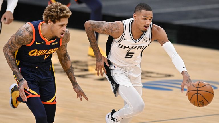 San Antonio Spurs&#39; Dejounte Murray (5) and Golden State Warriors&#39; Kelly Oubre, Jr. chase the ball during the first half of an NBA basketball game, Monday, Feb. 8, 2021, in San Antonio. (AP Photo/Darren Abate)


