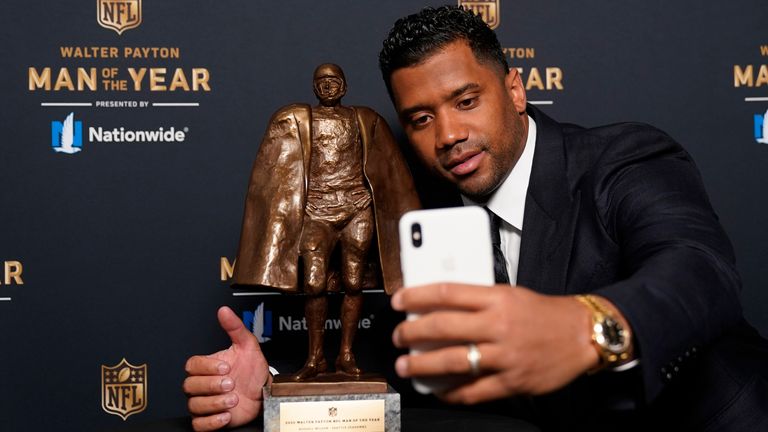 (Russell Wilson poses with the Walter Payton trophy (AP Photo/Charlie Riedel)