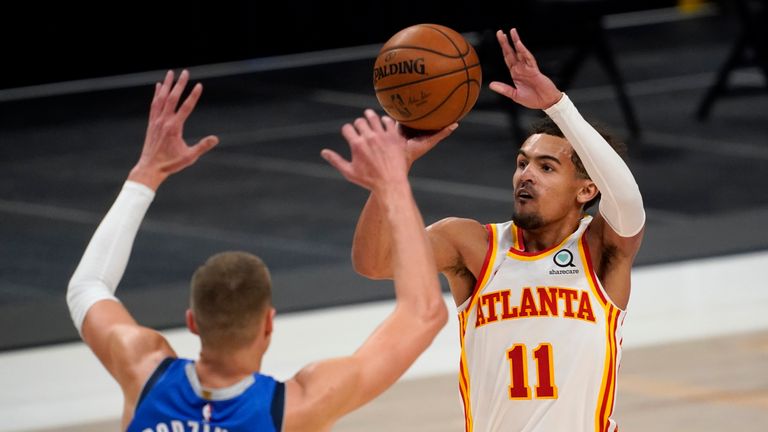 Dallas Mavericks&#39; Kristaps Porzingis defends as Atlanta Hawks guard Trae Young attempts a three-point basket