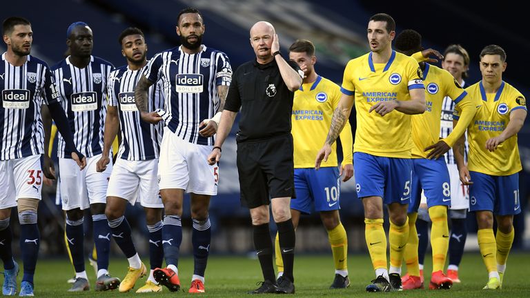 Players from both teams surround referee Lee Mason following confusion over Brighton's disallowed goal