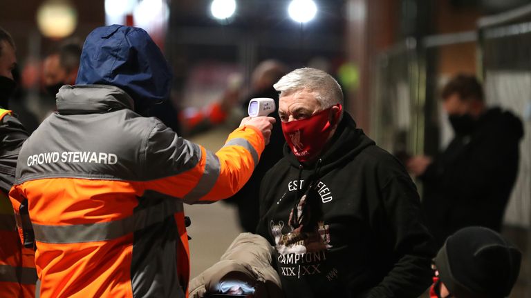 A Liverpool fan has his temperature checked before attending a Premier League match at Anfield