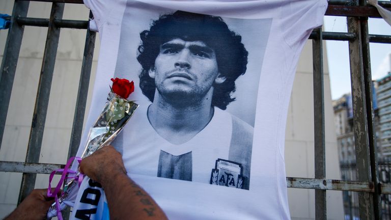 AP - A supporter attaches a rose next to a photo of Diego Maradona
