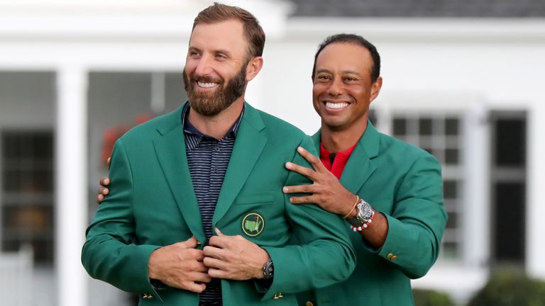 Last year's Masters champion Tiger Woods, right, presents Dustin Johnson with his first green jacket after winning the Masters