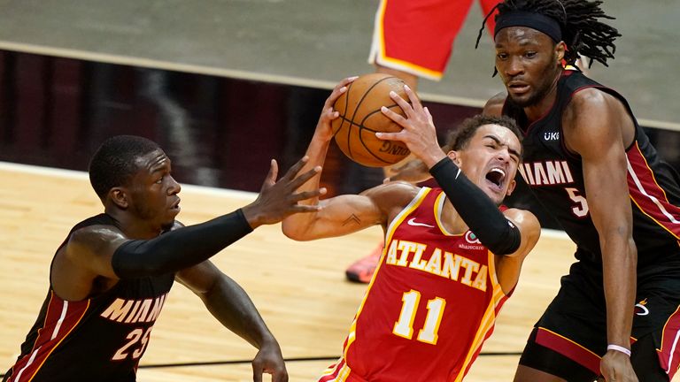 Atlanta Hawks guard Trae Young (11) drives to the basket as Miami Heat guard Kendrick Nunn (25) and forward Precious Achiuwa (5) defend during the first half of an NBA basketball game, Sunday, Feb. 28, 2021, in Miami.