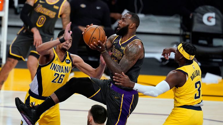 Los Angeles Lakers forward LeBron James, center, drives to the basket between Indiana Pacers guard Jeremy Lamb, left, and guard Aaron Holiday (3) during the first half of an NBA basketball game Friday, March 12, 2021, in Los Angeles.